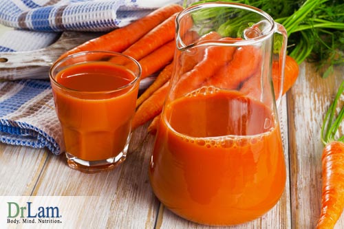A pitcher and glass of carrot juice and carrots in the background. Eating less while still taking in nutrients can help relax the liver and improve liver health.