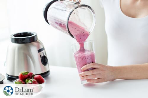 An image of a woman pouring strawberry smoothie from a blender