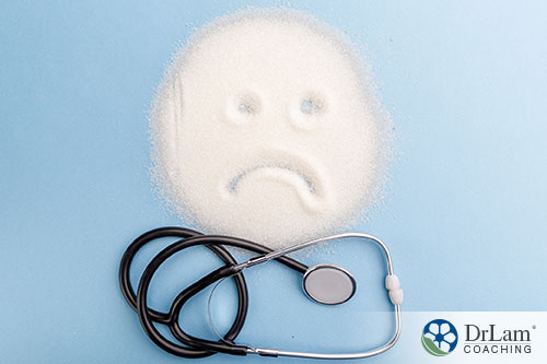 An image of a pile of sugar on a table with a frowning face drawn in it and a stethoscope